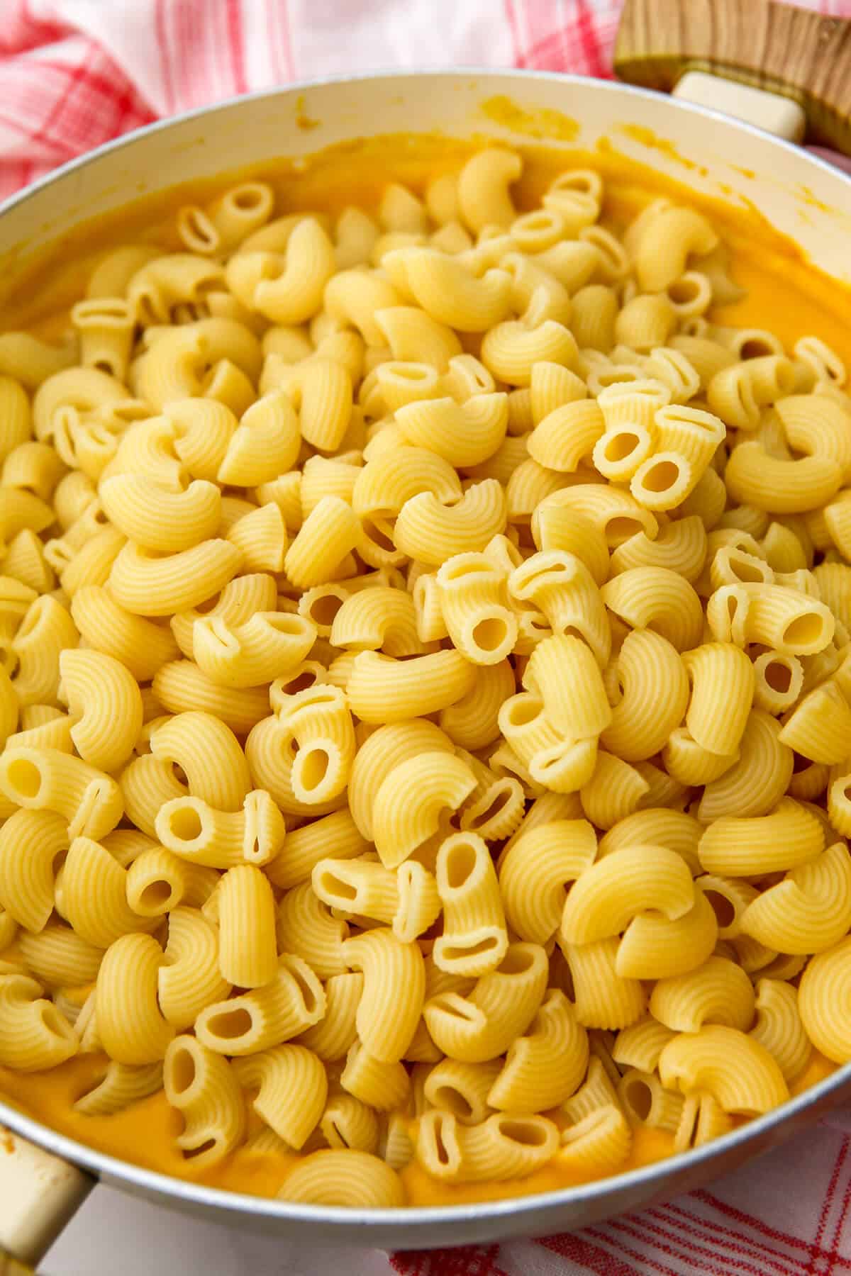 Pasta being added to a vegan cheese sauce before baking.