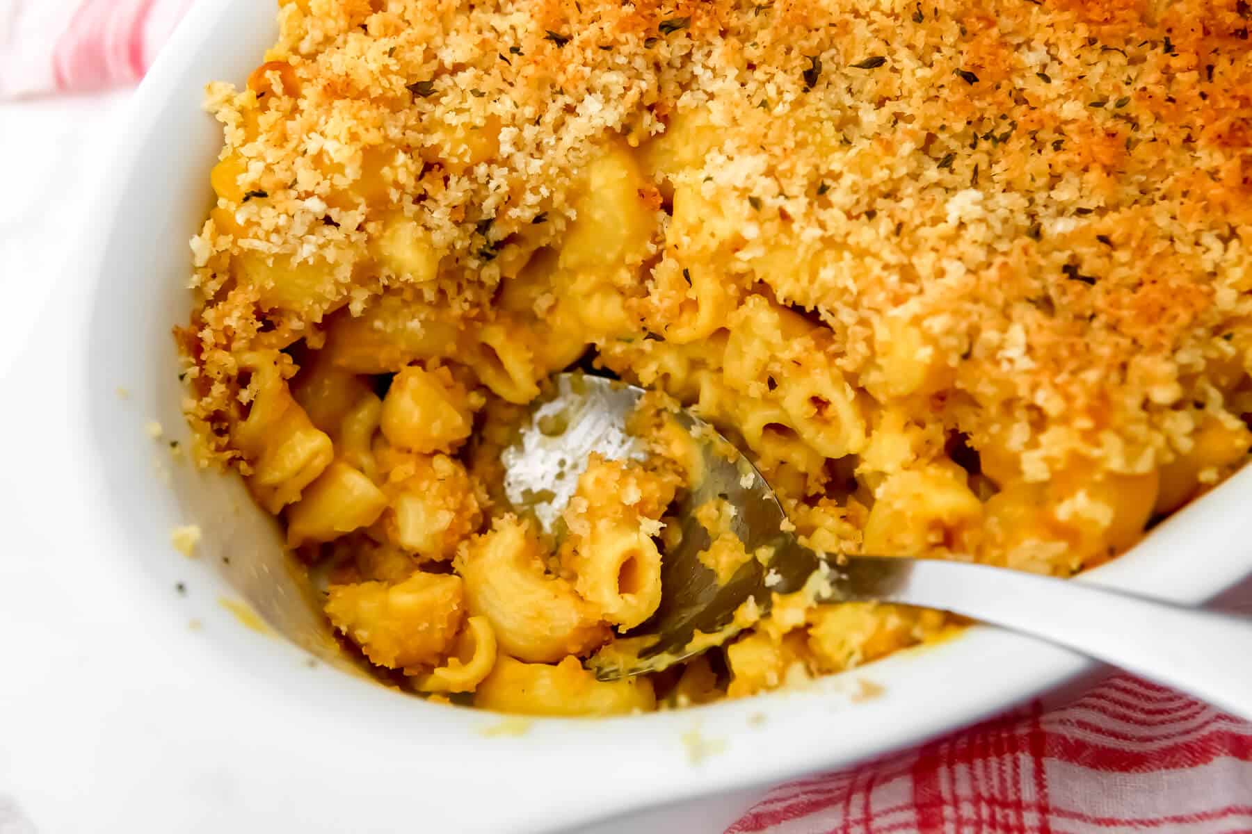 Vegan baked mac & cheese with a in a baking dish with a scoop taken out of it.