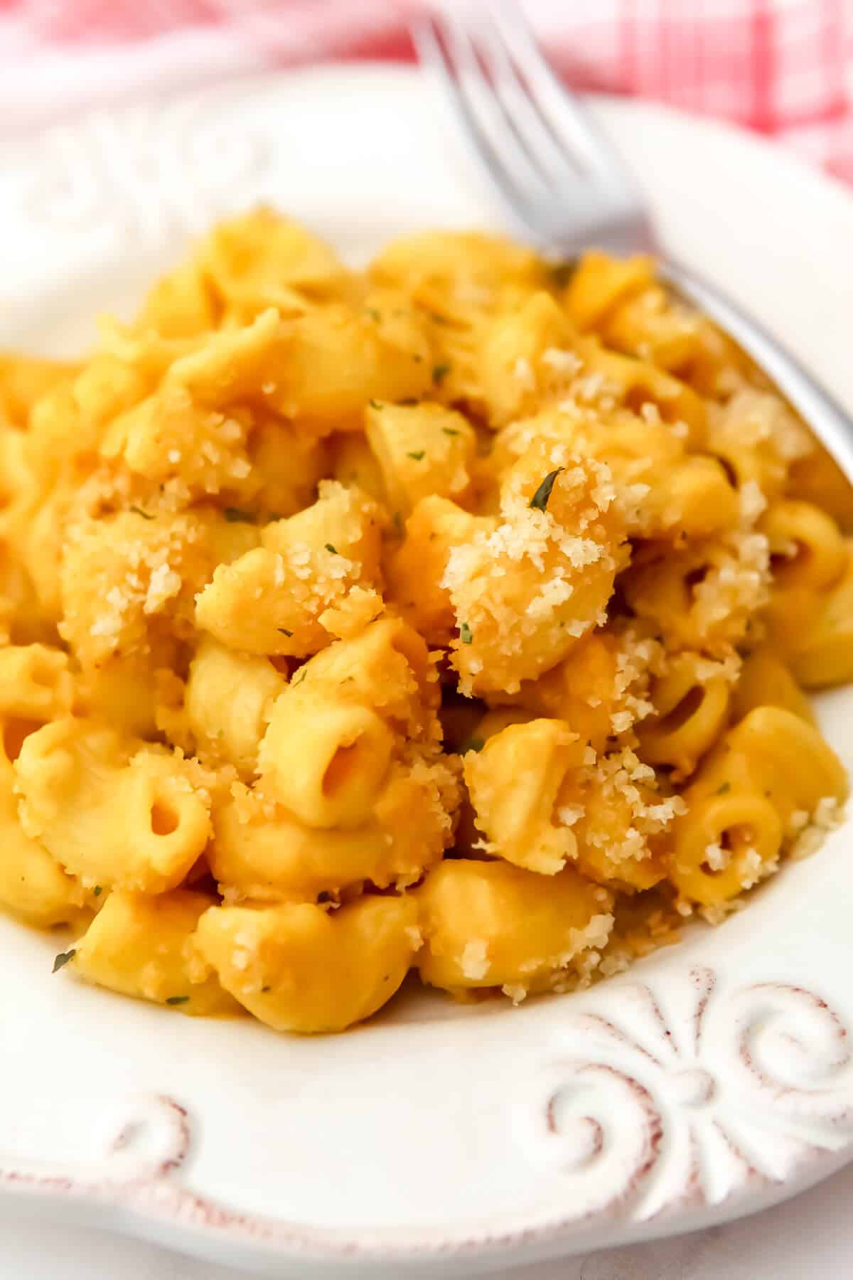 A white plate filled with vegan baked mac and cheese with a fork on the side.