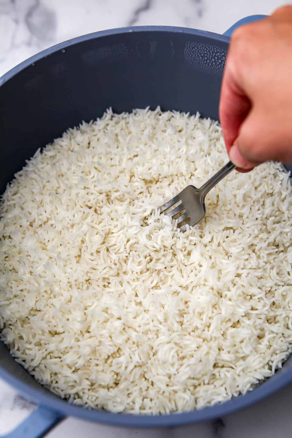 Cooked Basmati rice about to be fluffed with a fork.
