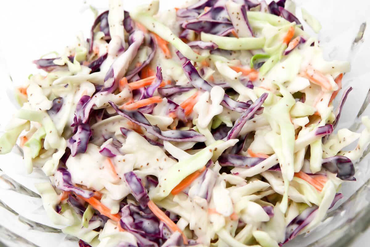 A close up of vegan coleslaw in a glass bowl.