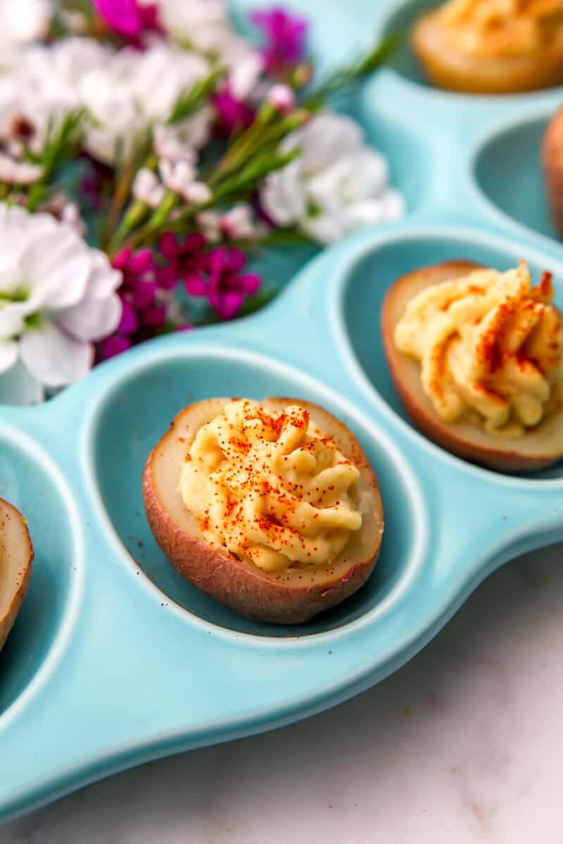 A close up of deviled potatoes on a blue deviled egg plate.