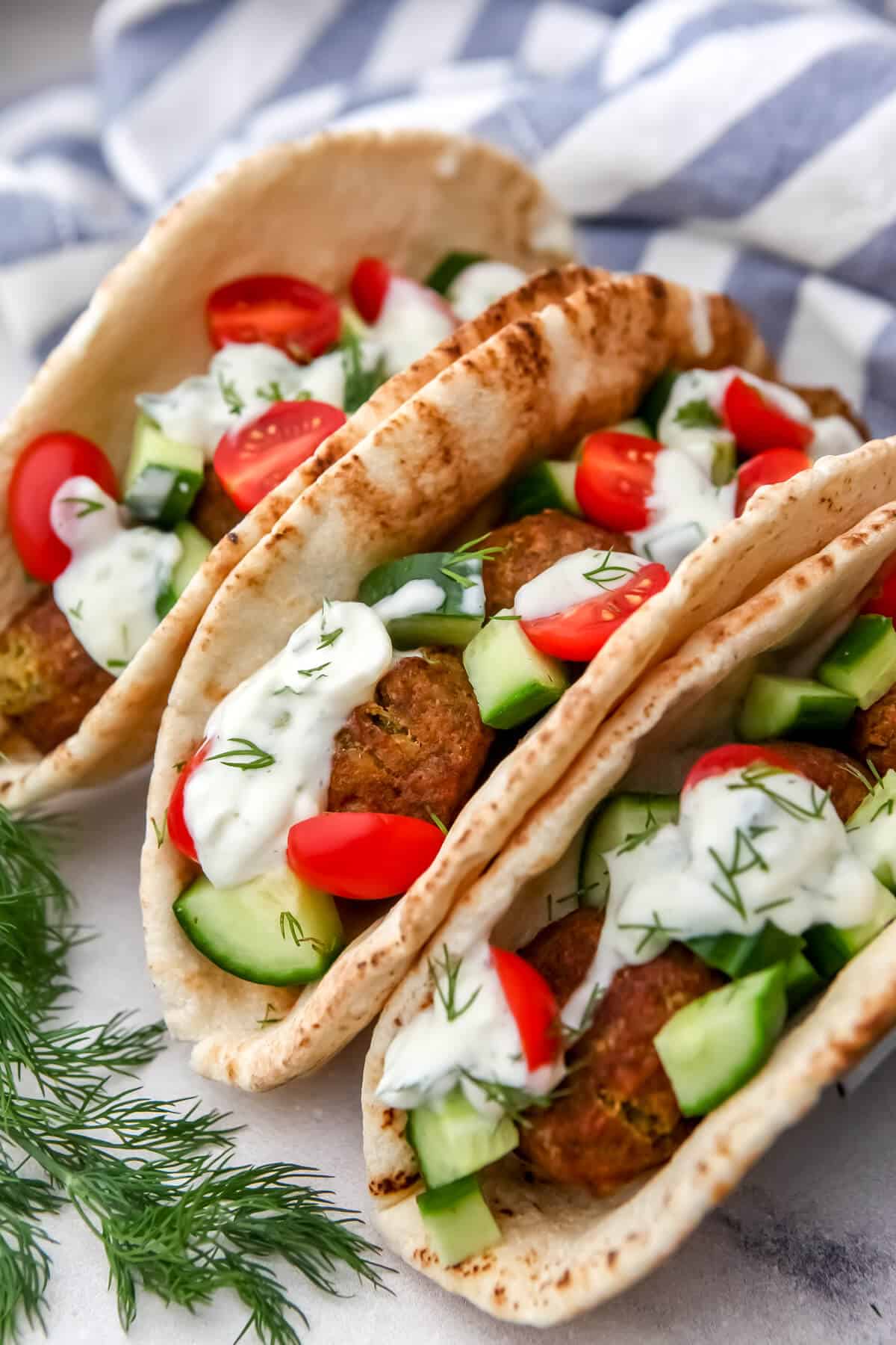 Three vegan falafel gyro wraps with vegan tzatziki sauce with fresh dill.