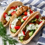 Three falafel gyros next to each other with a blue and white tea towel behind it.