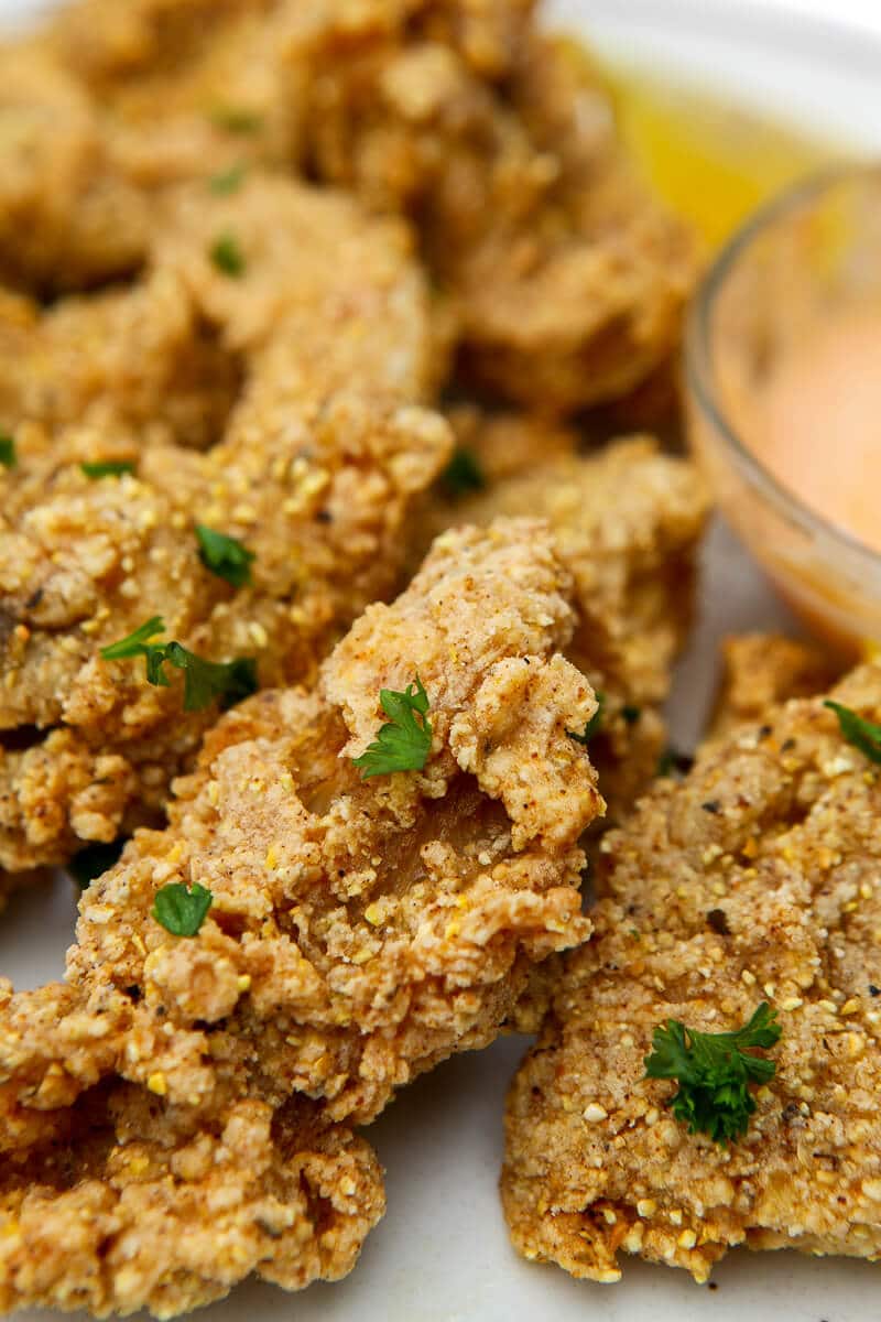 Deep fried oyster mushrooms with small pieces of parsley on top.