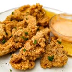 A white plate with deep-fried oyster mushrooms with vegan chipotle mayo on the side.