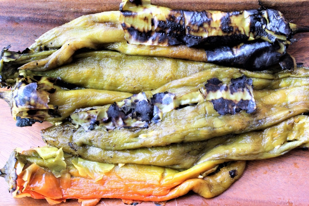 New Mexican green chiles roasted on a cutting board.