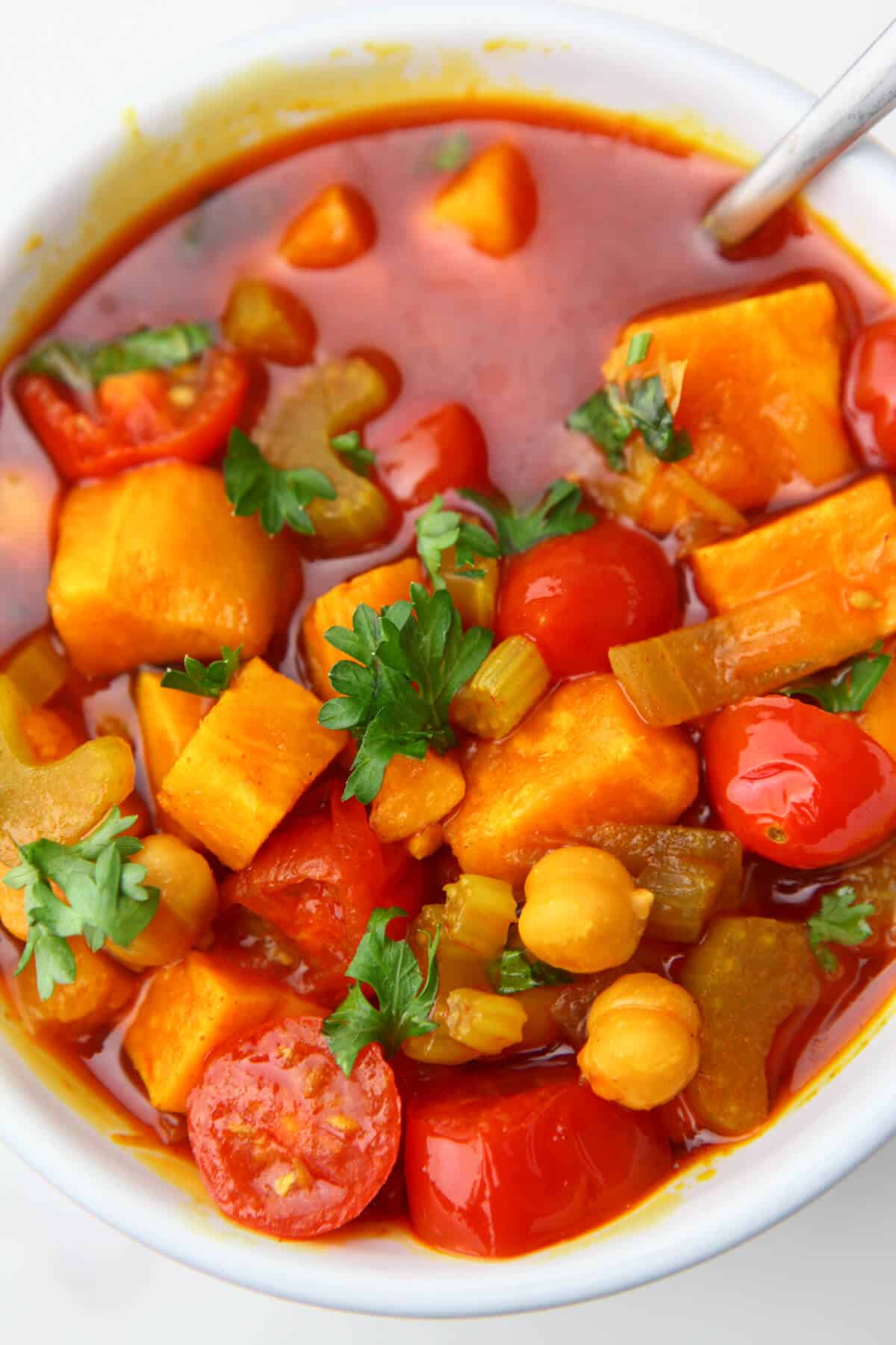 A top view of a bowl of gypsy soup with sweet potatoes, garbanzo beans, and cherry tomatoes.