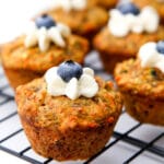 A close up of healthy vegan muffins with a dollop of frosting and a blueberry on top.