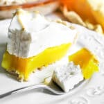 A close up of a slice of a classic vegan lemon meringue pie with aquafaba meringue topping and vegan lemon curd.