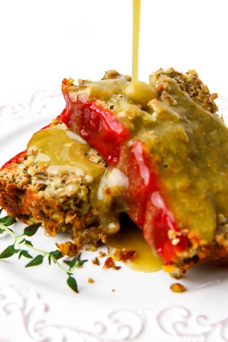 Two slices of lentil loaf with vegan gravy being poured over top of it.