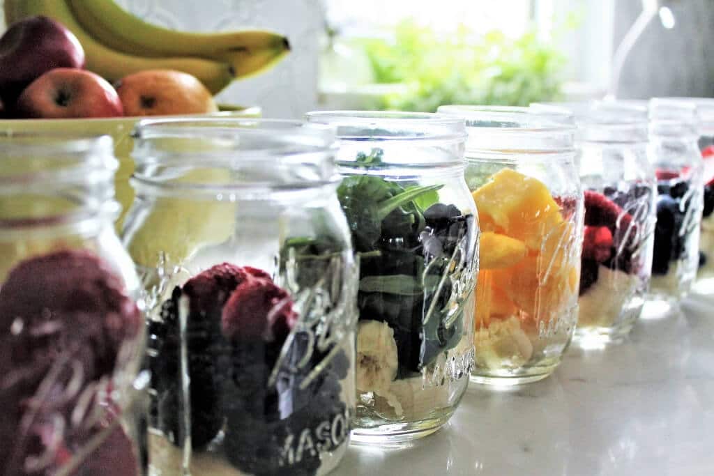 A line of mason jars filled with bananas and fruit to make 12 make ahead smoothies.