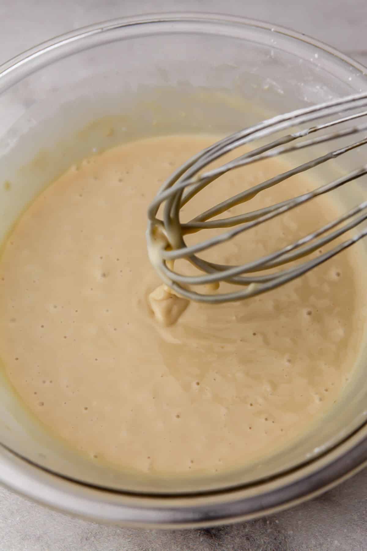 Vegan vanilla cupcake batter stirred with a whisk.