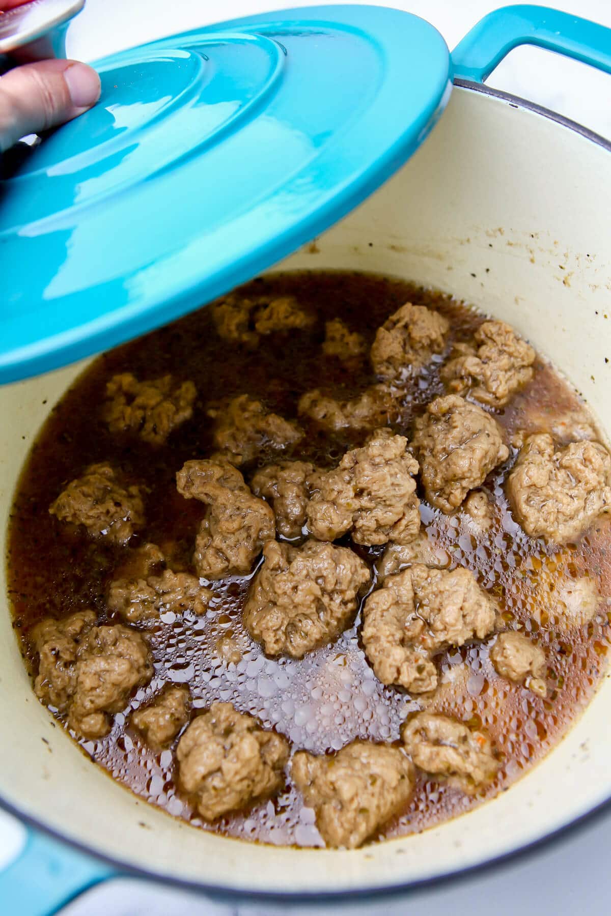 Seitan chunks simmering in a large blue pot.