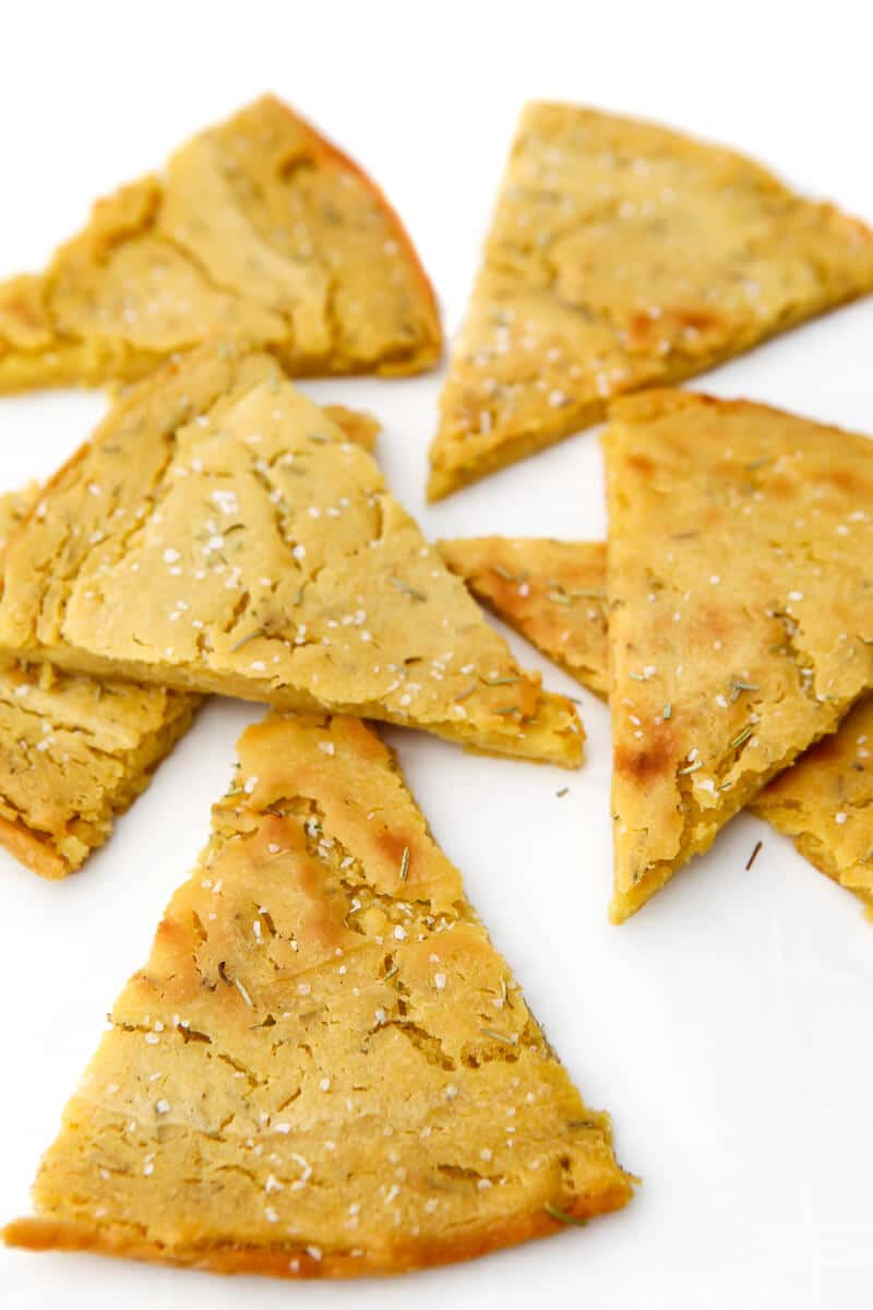 Wedges of Socca chickpea flour flat bread on a white surface.