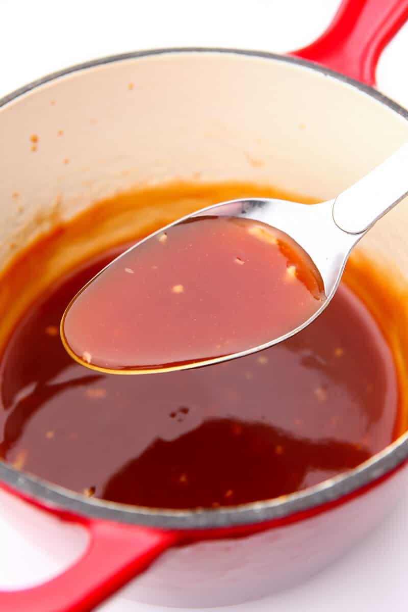 A red sauce pan filled with homemade sweet and sour sauce.