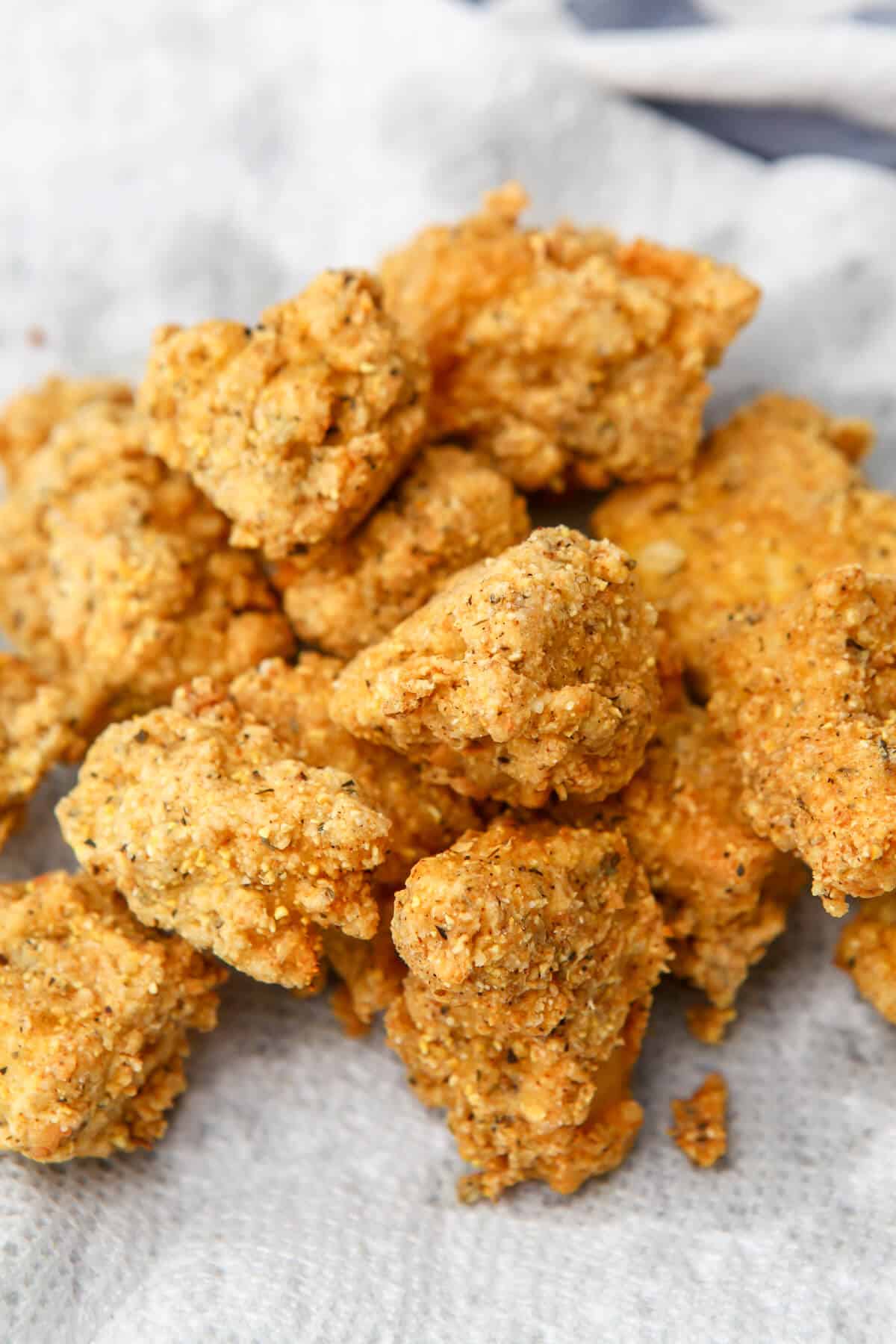 Pieces of KFC style vegan fried chicken on a paper towel after frying.