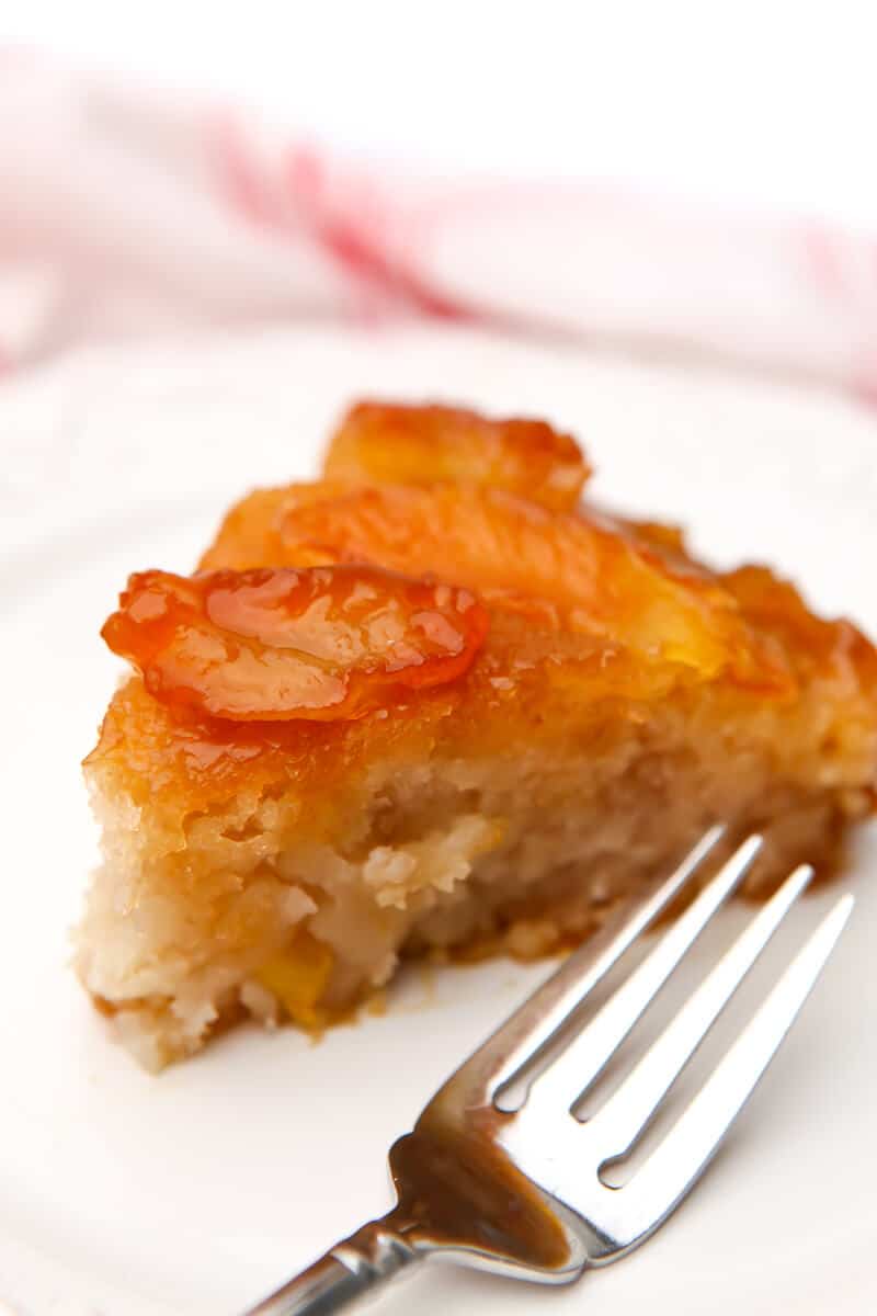 A slice of vegan apple cake on a white plate with a fork on the side.