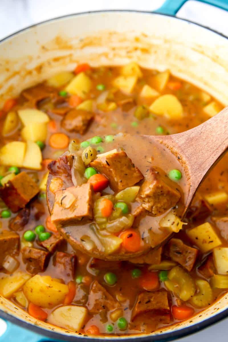 A large blue dutch oven filled with vegan beef stew.