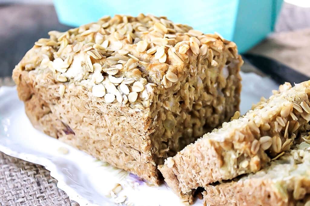 A loaf of easy vegan beer bread sliced with oats on top.