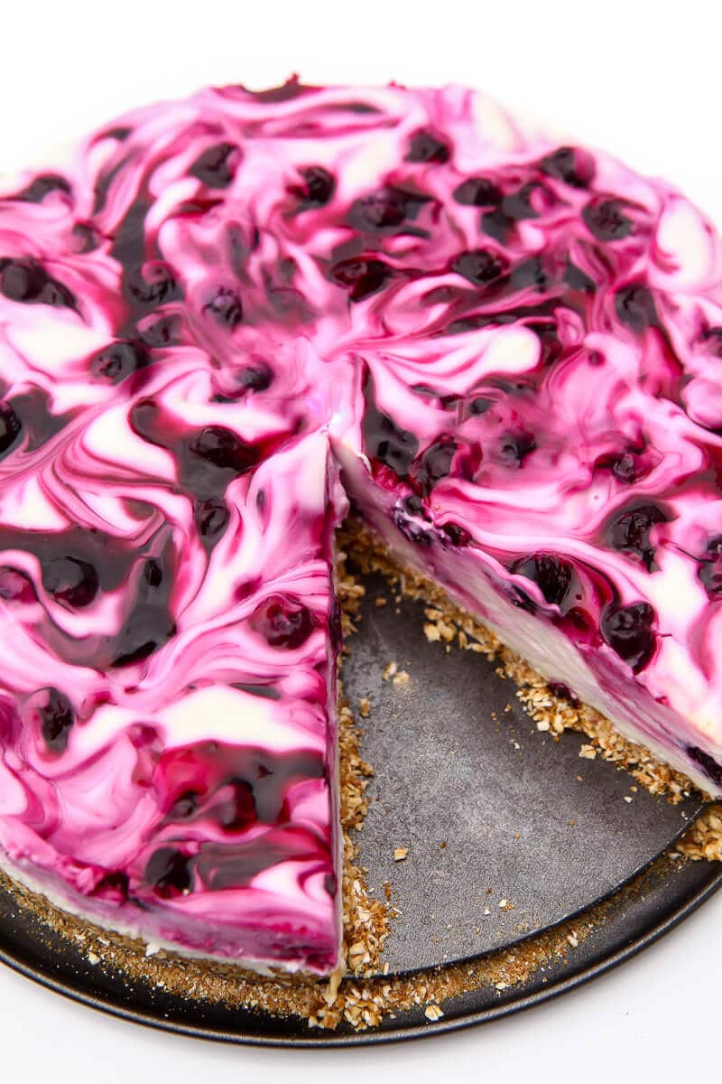 A top view of a no bake vegan blueberry cheesecake with a slice taken out of it.