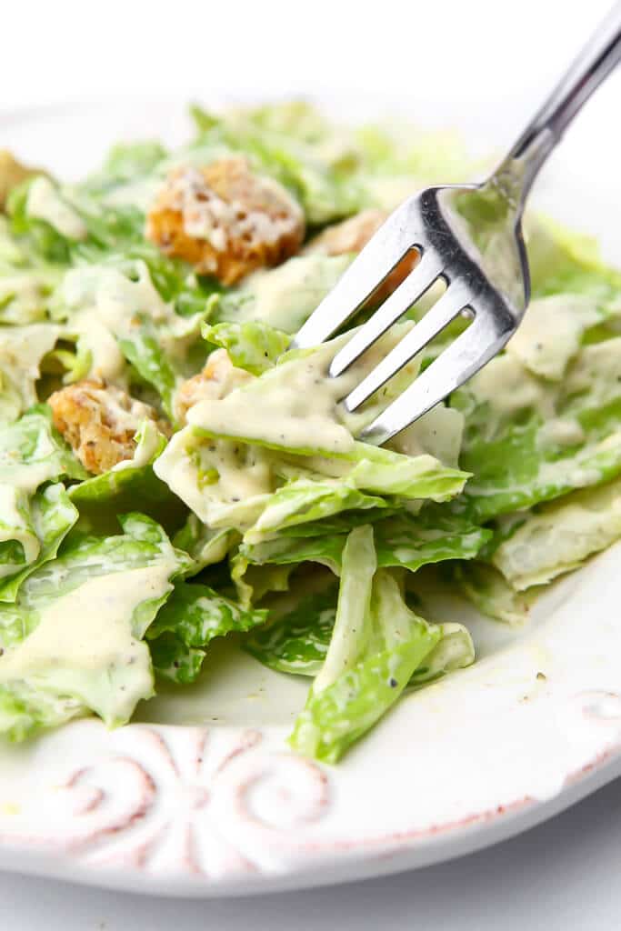 A close up of a fork full of romaine lettuce with vegan Caesar dressing on it.