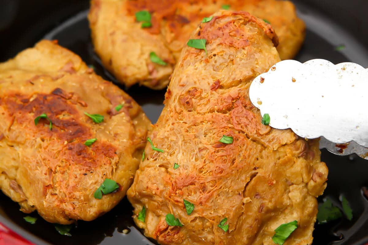 Vegan chicken breasts in a frying pan.