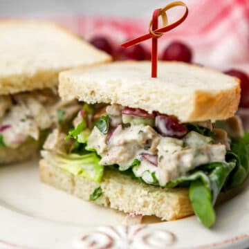 A vegan chicken salad sandwich on white bread sliced in half on a white plate.