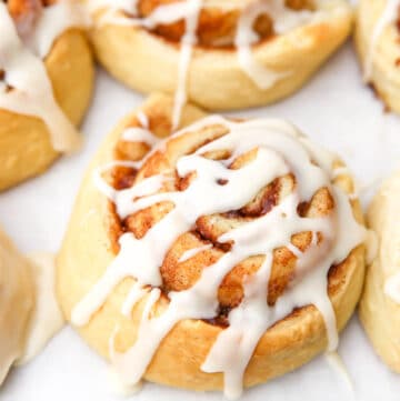 A close up of a vegan cinnamon bun with icing drizzled on top.
