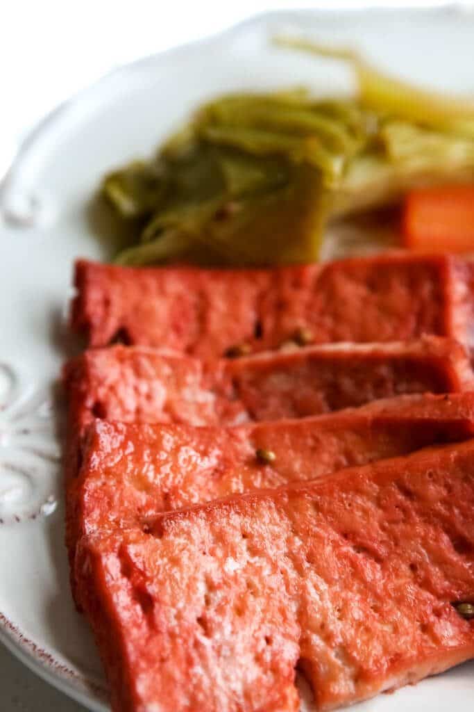 A white plate filled with vegan corned beef and cabbage.