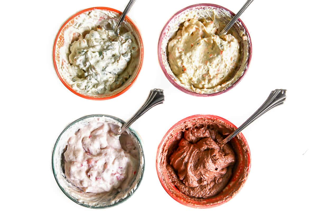 Four small colorful bowls with 4 different flavors of tofu cream cheese in them.