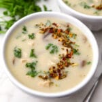 A bowl of vegan cream of chicken soup with a spoon on the side.