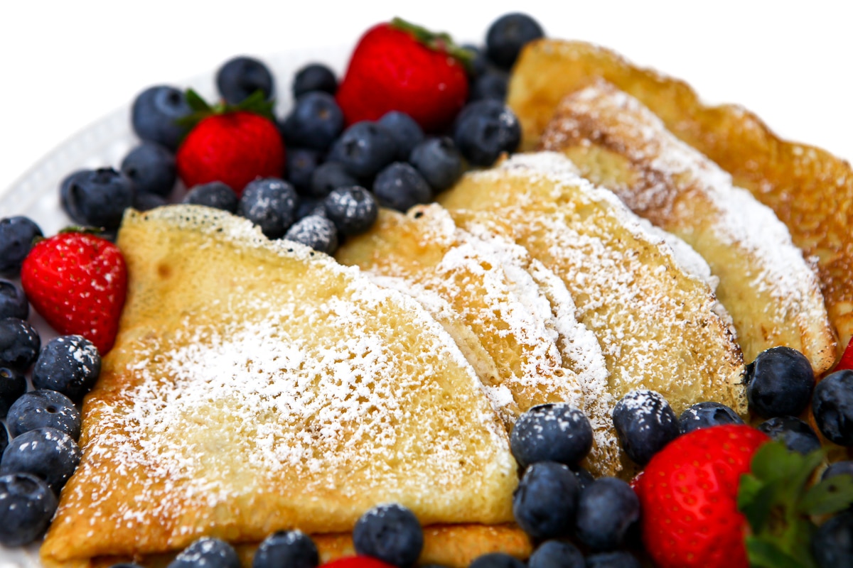 Vegan crepes folded into triangles and dusted with powdered sugar.