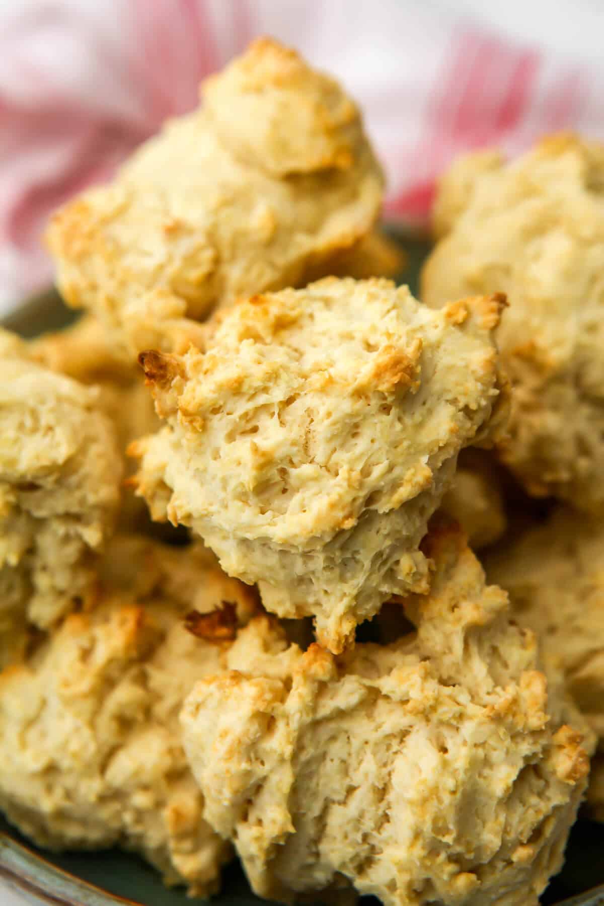 Vegan drop biscuits on a plate with a red and white tea towel behind it.