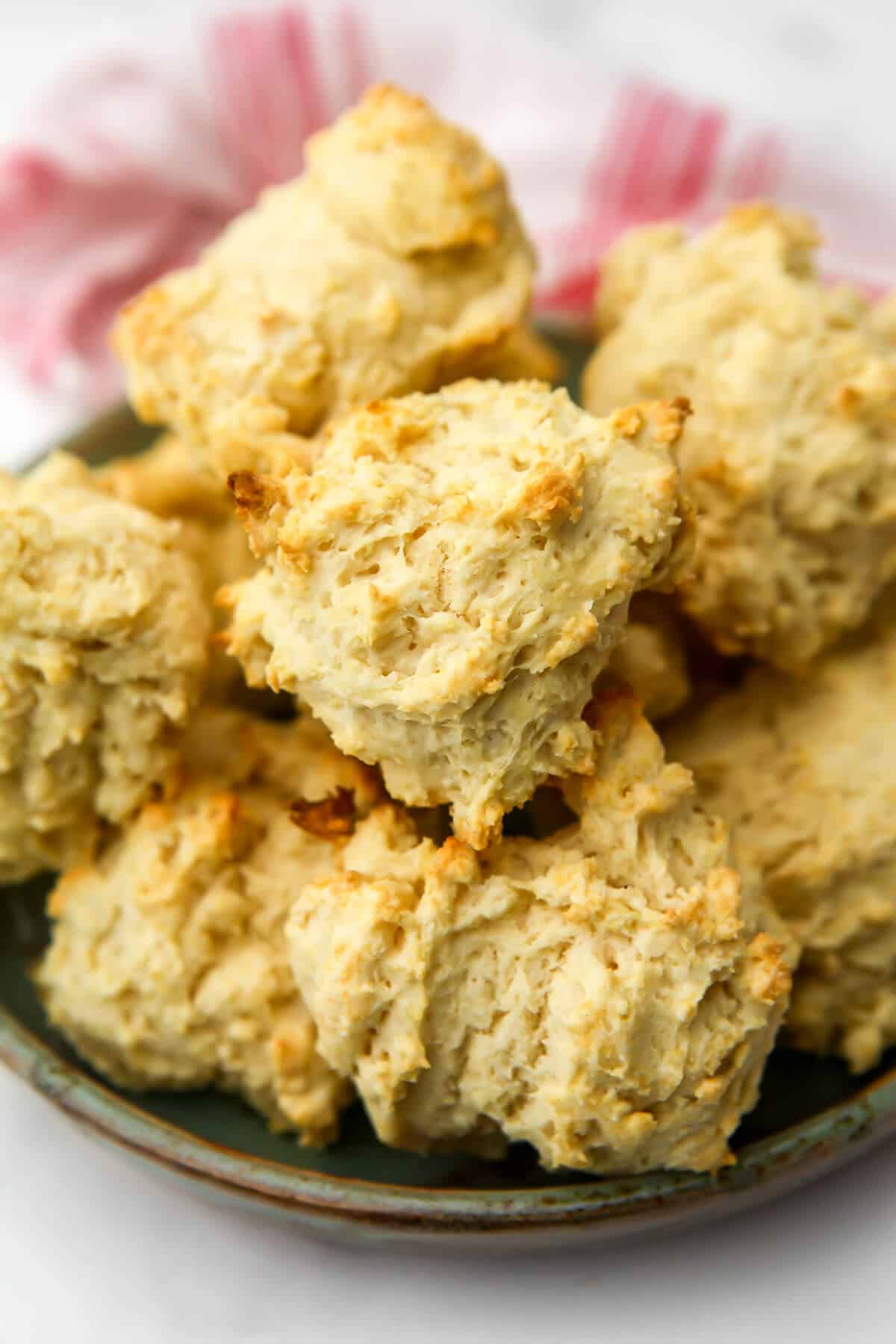 Vegan drop biscuits stacked on a plate.