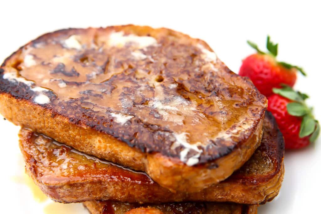 A stack of 3 pieces of egg-free French toast with butter and syrup on top.