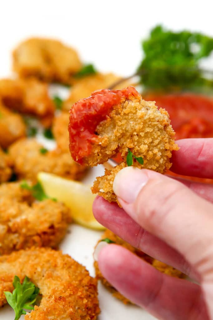 A deep fried vegan shrimp dipped in cocktail sauce.