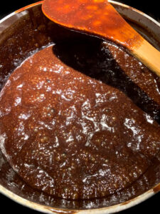 The fudge sauce once it has reached 230°F, lower in the pan and darker.