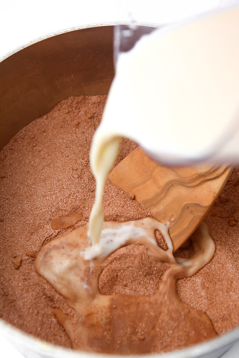 Pouring soy milk into dry ingredients to make dairy-free fudge.