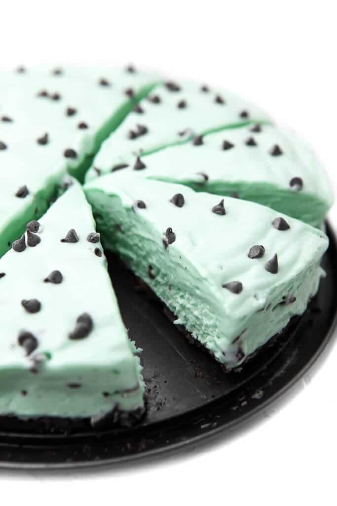 A vegan mint chocolate chip pie cut into pieces on the pie plate.