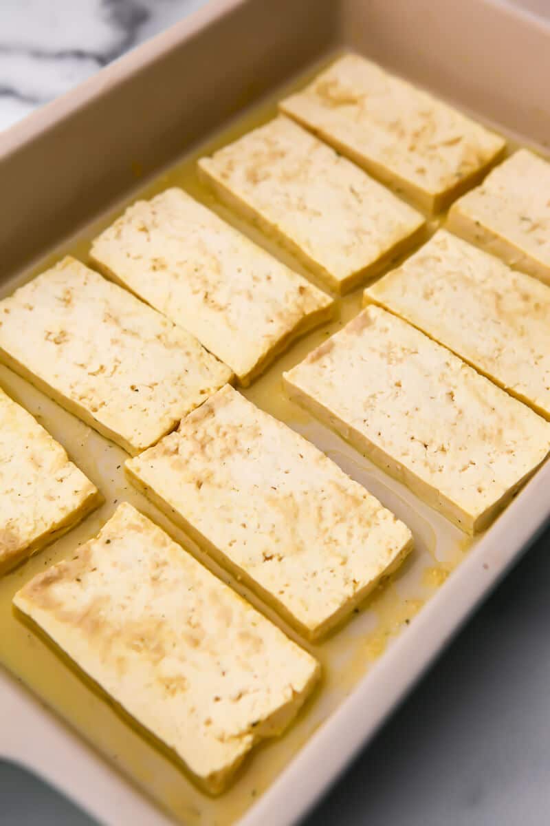 Tofu marinating in a large dish of cheesy salty brine to give it the taste of Halloumi cheese.