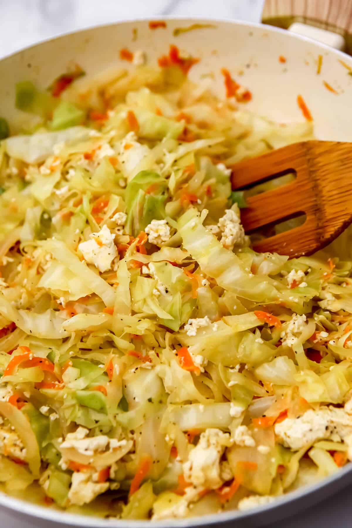 A large frying pan filled with onions, cabbage, carrots and tofu before adding the noodles to make haluski.