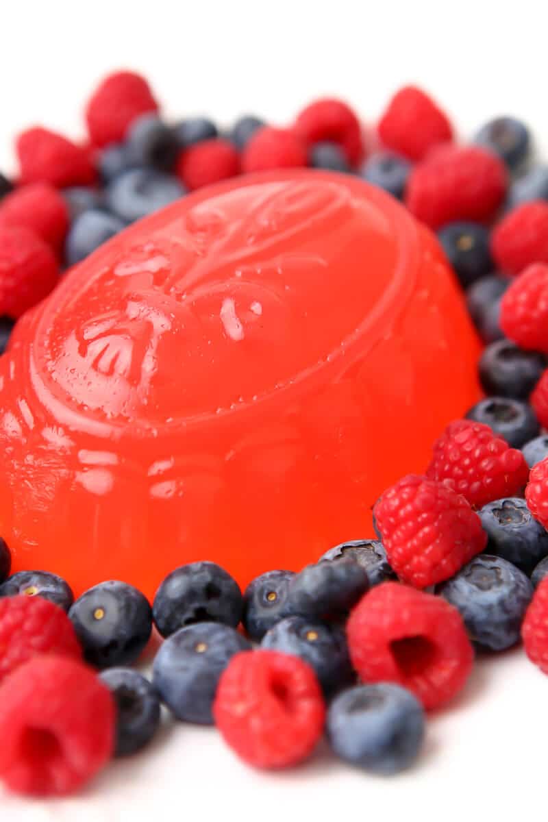 A jello mold made with vegan gelatin with berries around it. 