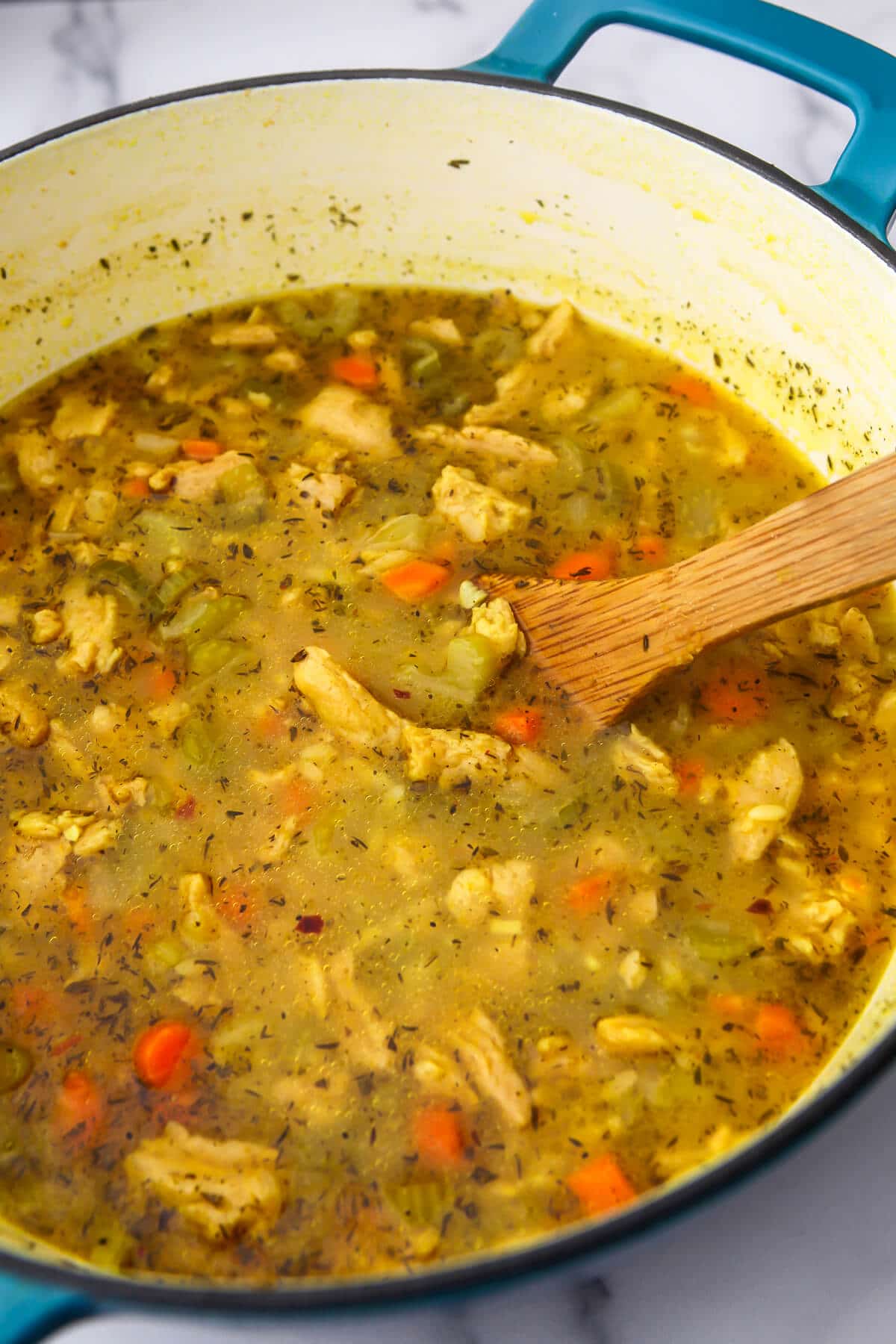 Vegan orzo soup in a lage soup pot with orzo and vegan chicken added.