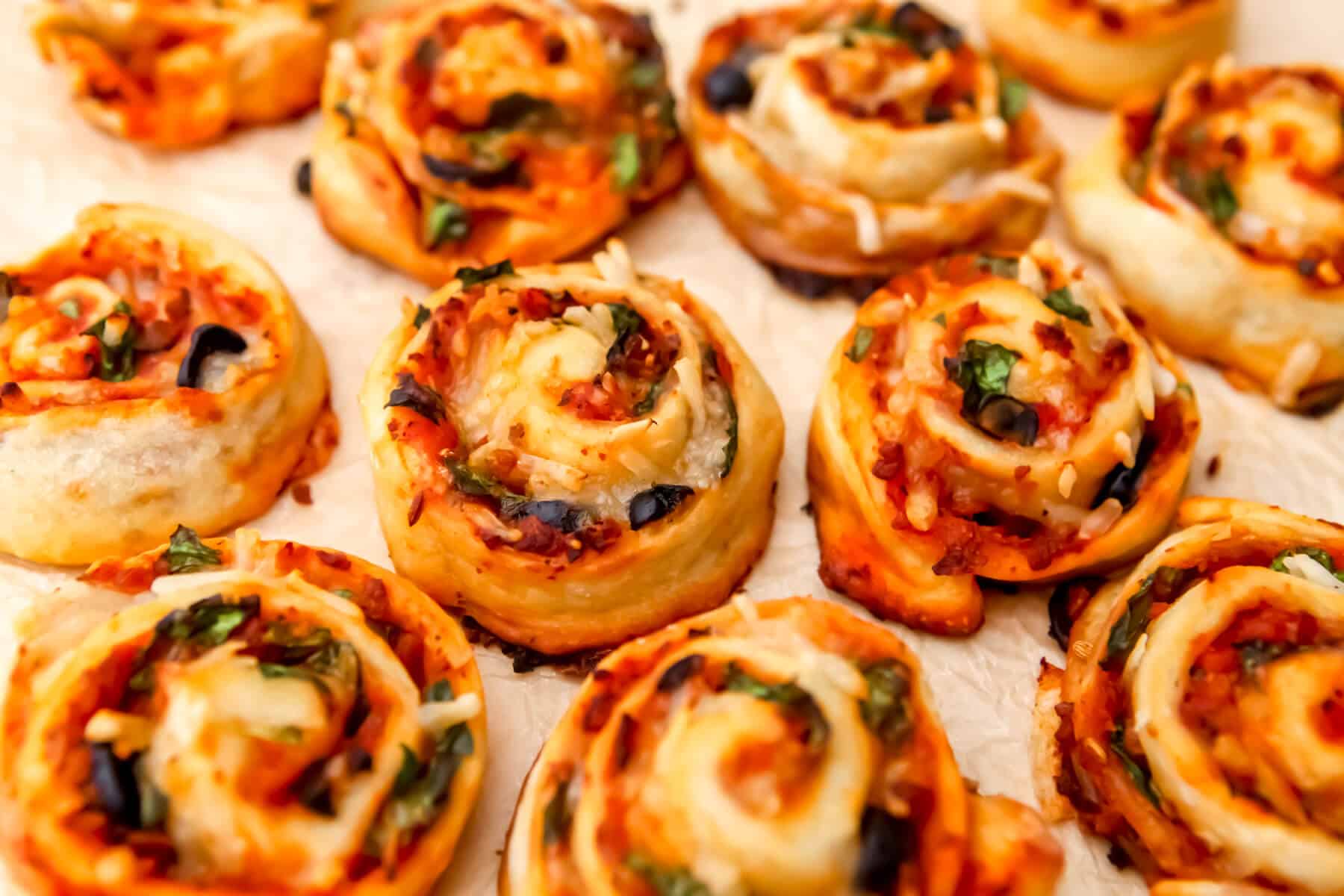 A dozen vegan pizza rolls cooling on a countertop.