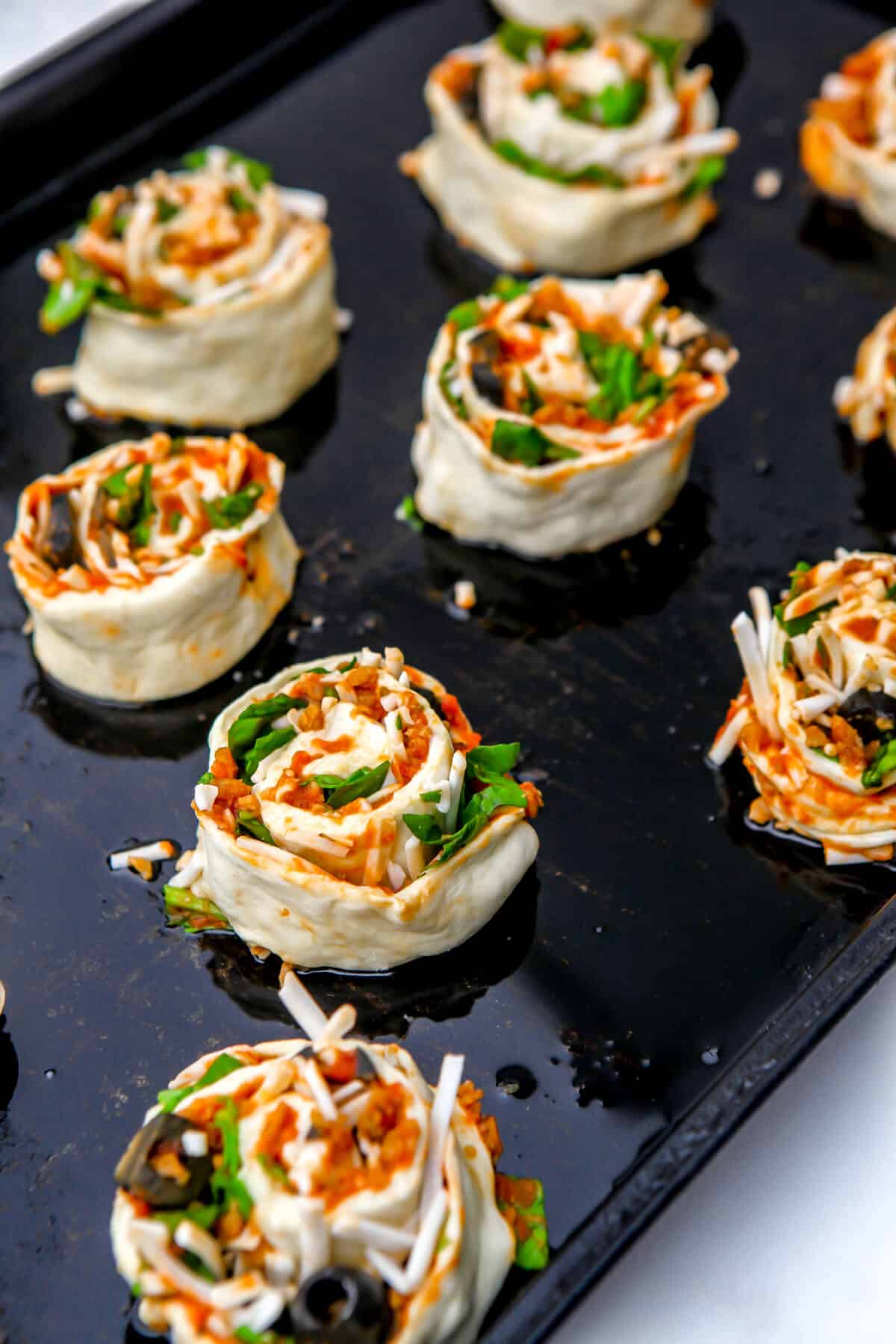 Vegan pizza rolls on a baking sheet before they are baked.