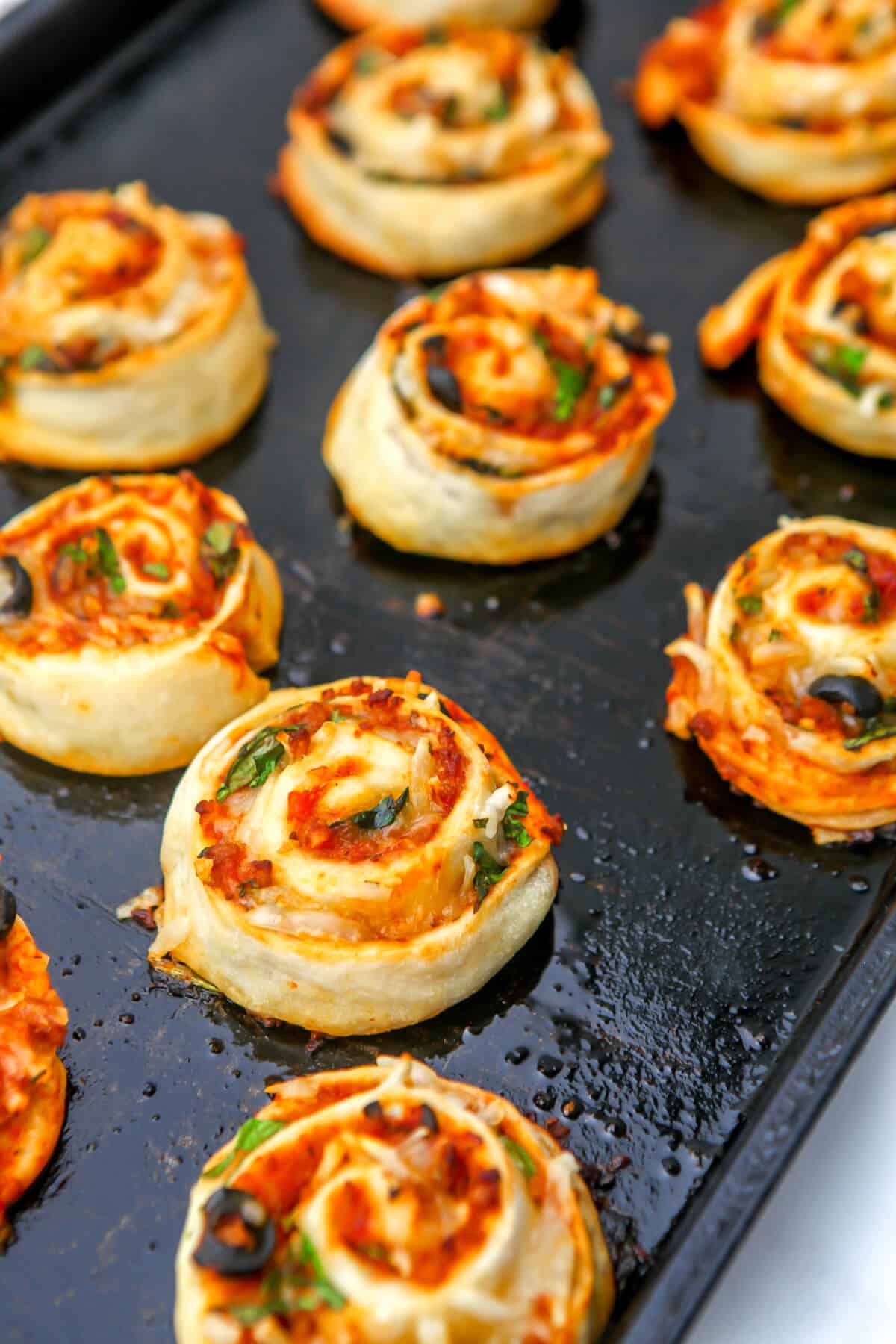 Vegan pizza rolls filled with cheese, spinach, and black olives after they have been baked.