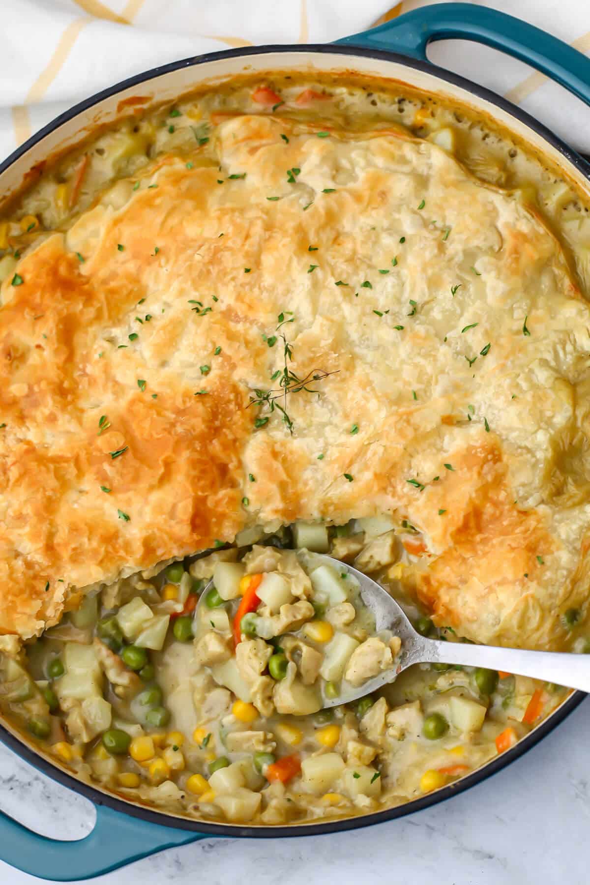 A top view of a vegan pot pie made in a large blue skillet and topped with puff pastry.