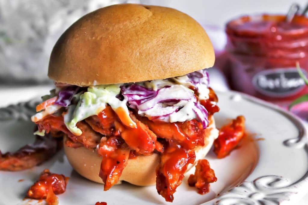 A gluten free vegan pulled pork sandwich with vegan coleslaw on a Schar brand bun.