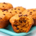 A close up of a chocolate chip pumpkin muffin with a bite taken out of it.